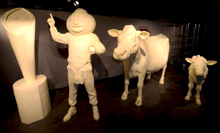 A buttery Brutus Buckeye and national championship trophy join annual favorites the butter cow and calf at the 2015 Ohio State Fair. This year`s theme, sponsored by the American Dairy Association Mideast, honors the Ohio State Buckeyes` 2015 football national championship victory. The display includes two Ohio State football helmets and a life-size replica of head football coach Urban Meyer. Fairgoers can view the butter display at the fair from July 29 to August 9.